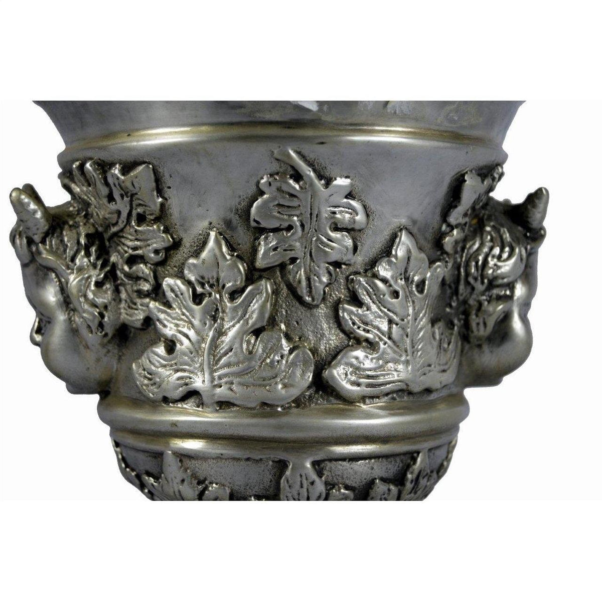 Close-up of silver plate urn with ornate leaf patterns, sculpted faces, and figural cherub ornaments.