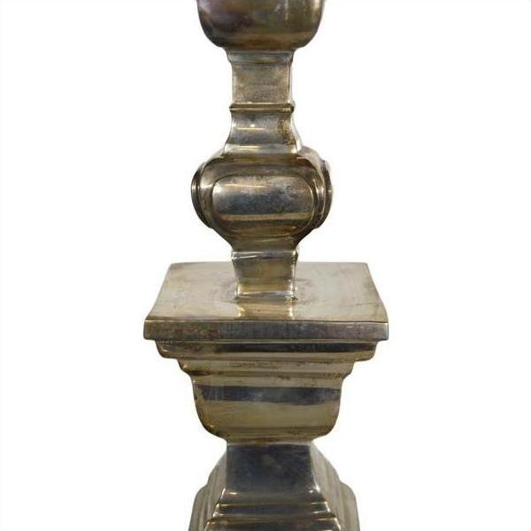 Close-up of a silver plated candle holder with square base and rounded decorative details.