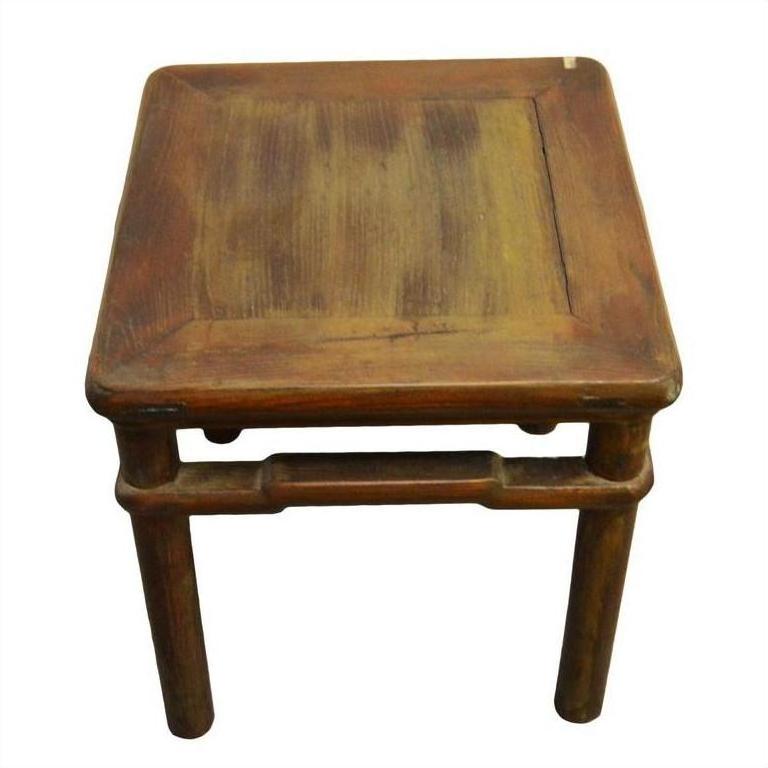 Natural elm wood table or stool with four legs and a slightly worn finish, close-up.