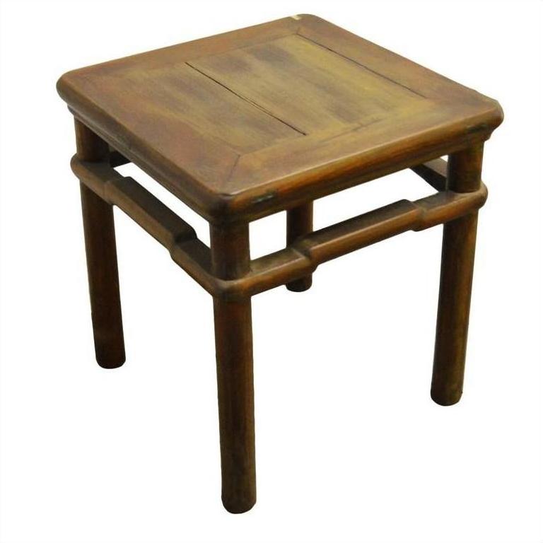 Close-up of a small, square natural-stain elm wood table or stool with four round legs.