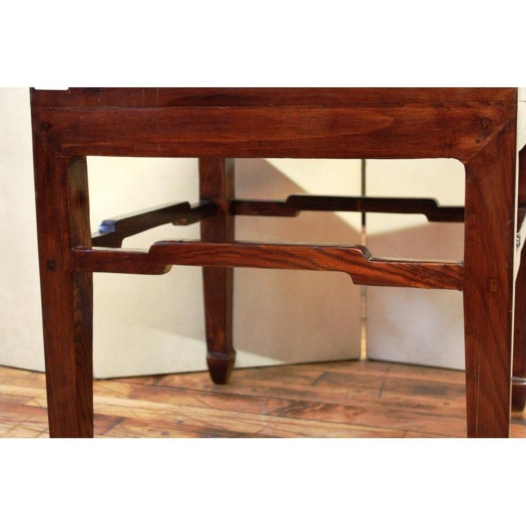 Close-up of light wood square table legs with curved stretcher, on wood floor against a light background.