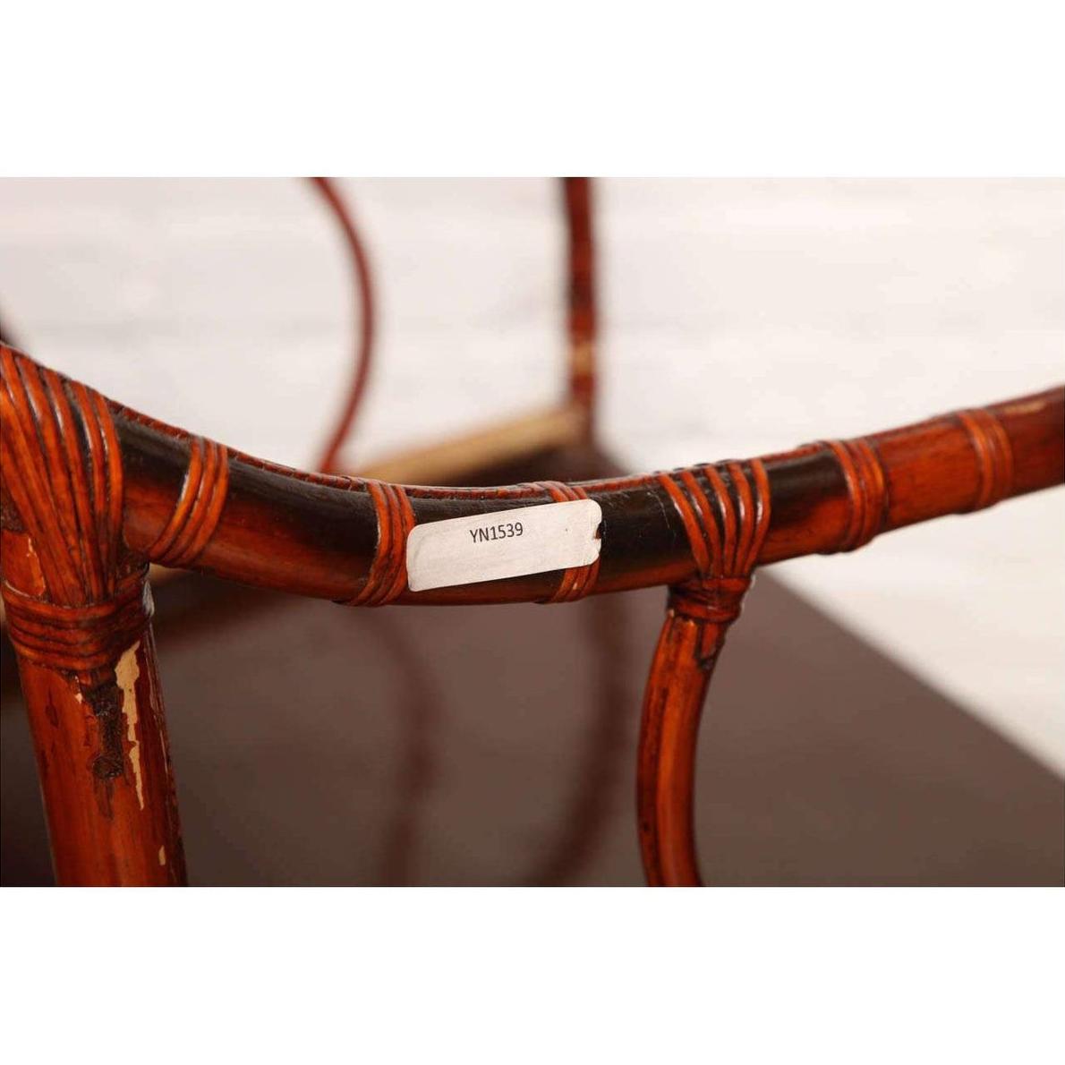 Close-up of a brown bamboo and elm horseshoe-back armchair with visible white label on the armrest. 19th century.