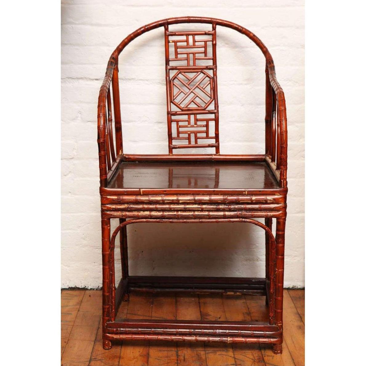 Brown bamboo and elm horseshoe-back armchair on wooden floor against a white wall indoors.