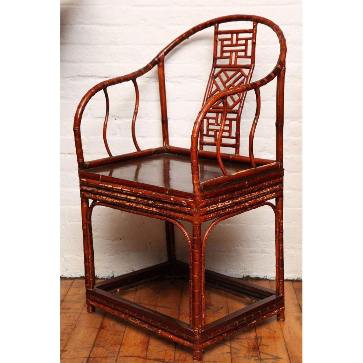 Brown bamboo and elm horseshoe-back armchair on wooden floor beside a white brick wall indoors.
