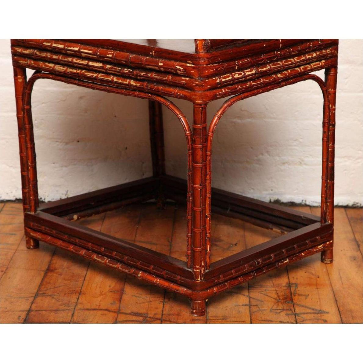 Brown bamboo and elm horseshoe-back armchair next to bamboo side table, lower half view indoors.