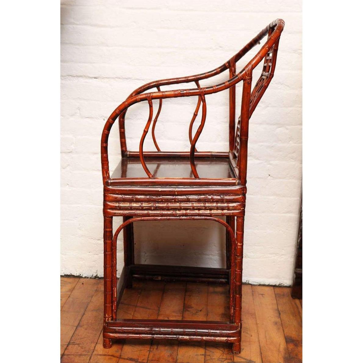 Brown bamboo and elm horseshoe-back armchair placed indoors by a white brick wall and wooden floor.