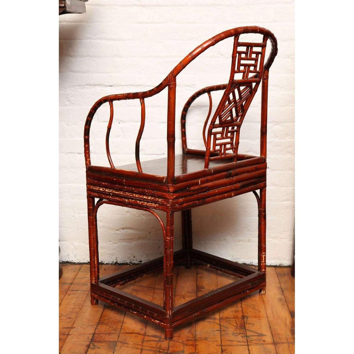 Brown bamboo and elm horseshoe-back armchair on a wooden floor indoors, 19th century Chinese style.