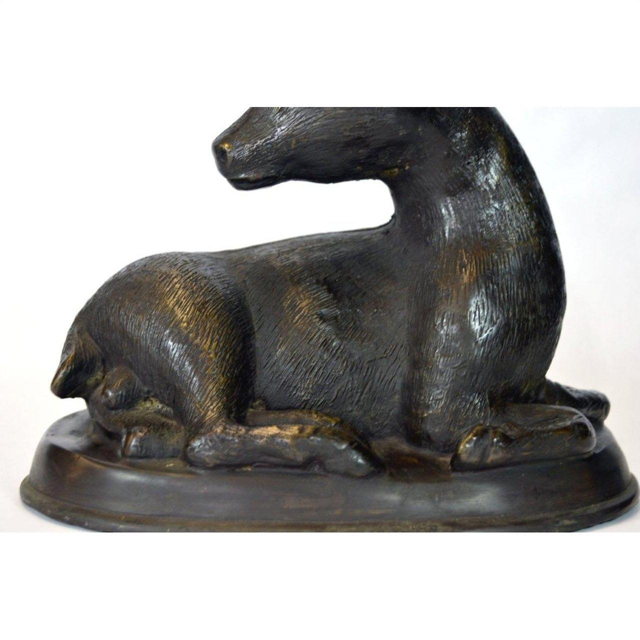 Bronze sitting deer sculpture on oval base, head turned left, close-up view, very good condition.