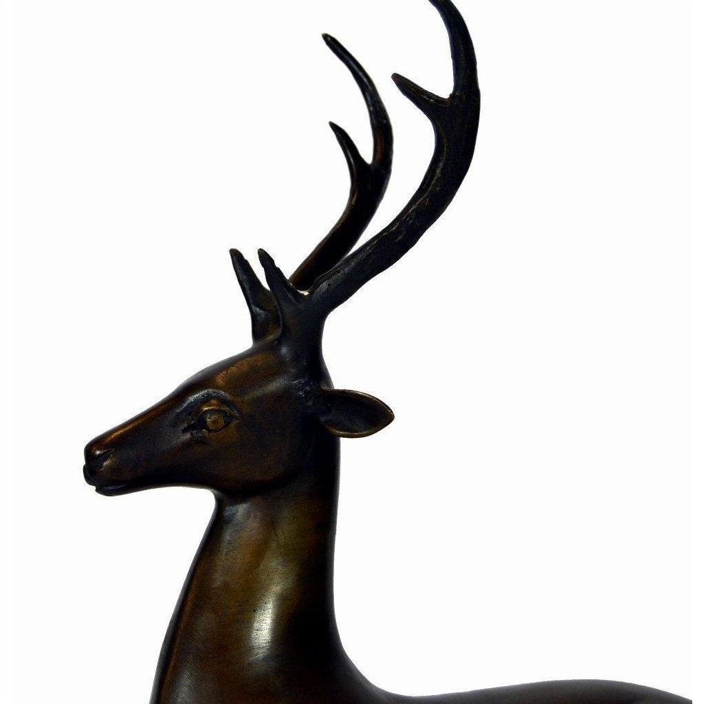 Bronze sitting deer sculpture with large antlers on a marble base, shown against a plain white background.