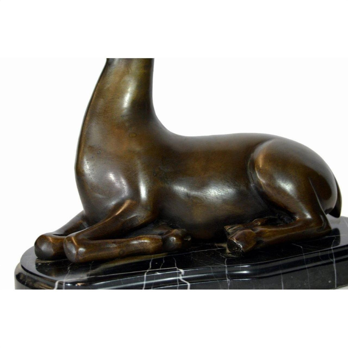Close-up of bronze sitting deer sculpture on marble base, shown from neck down.