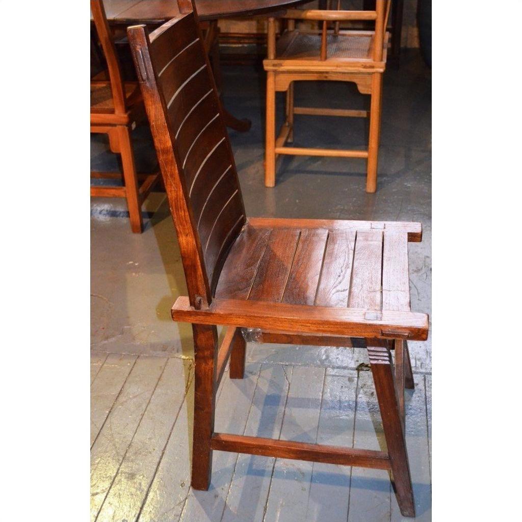 Brown wooden Arts &amp; Crafts style chair with tall backrest and flat seat on indoor wooden floor.