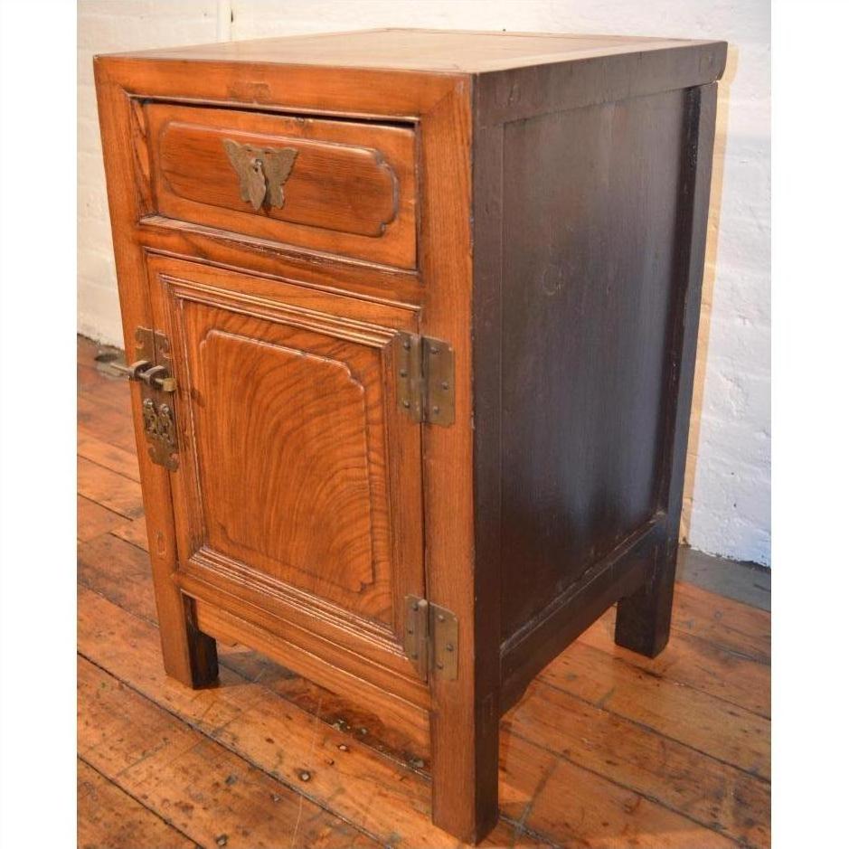 Wooden side cabinet with butterfly brass hardware, latch, drawer, and door on a wooden floor.