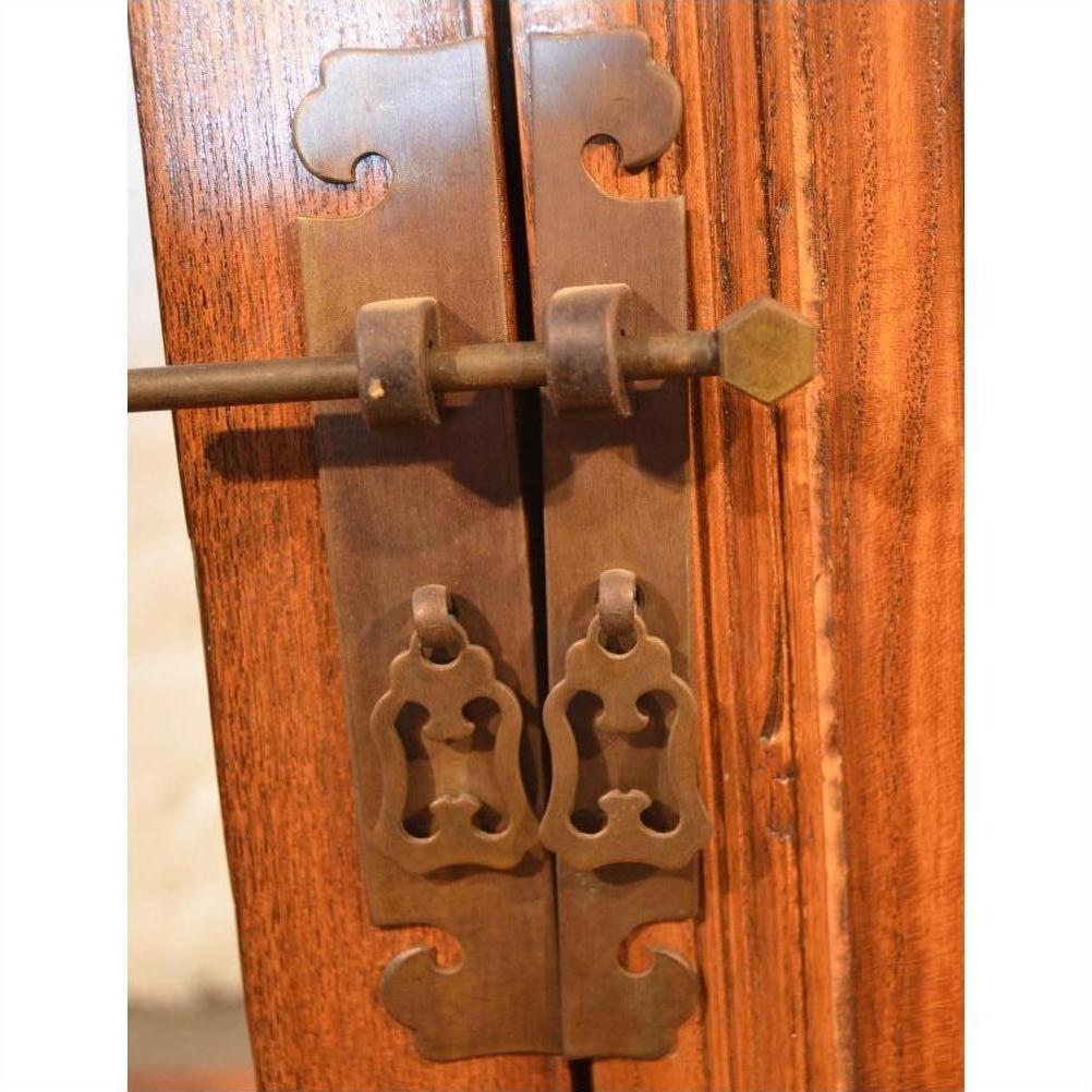 Close-up of butterfly-shaped brass hardware on a wooden door of the Small Side Cabinet.