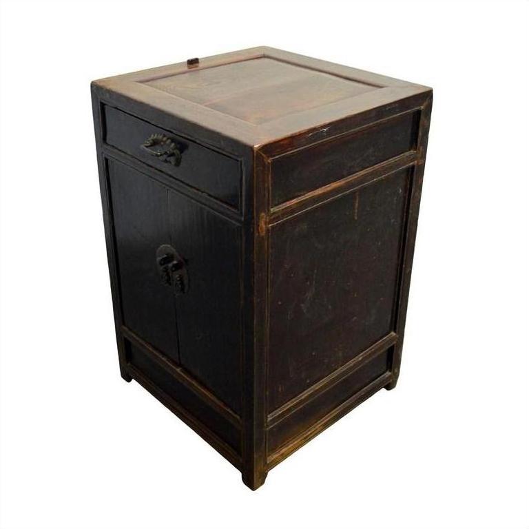 Close-up of dark wood antique carved side cabinet with brass medallion, one drawer, and door, lightly worn finish.