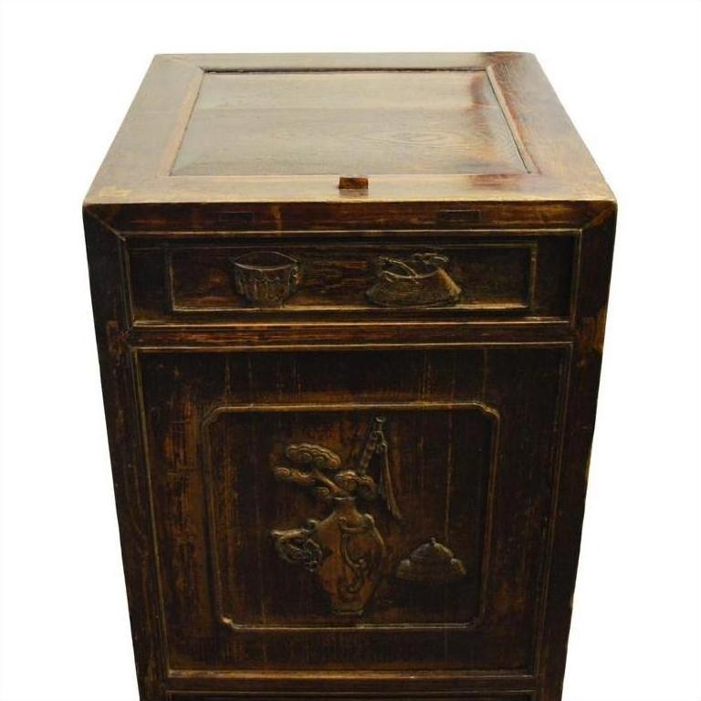Dark wood carved side cabinet with hand-carved details and brass medallion on front panel and drawer, studio view.