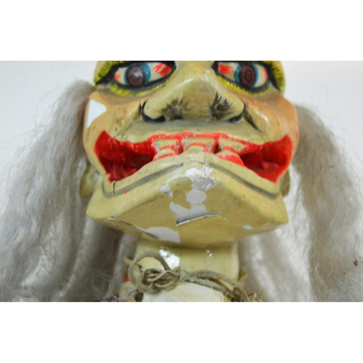 Close-up of a Taiwan Opera Doll with a worn, painted face, exaggerated features, and white hair.