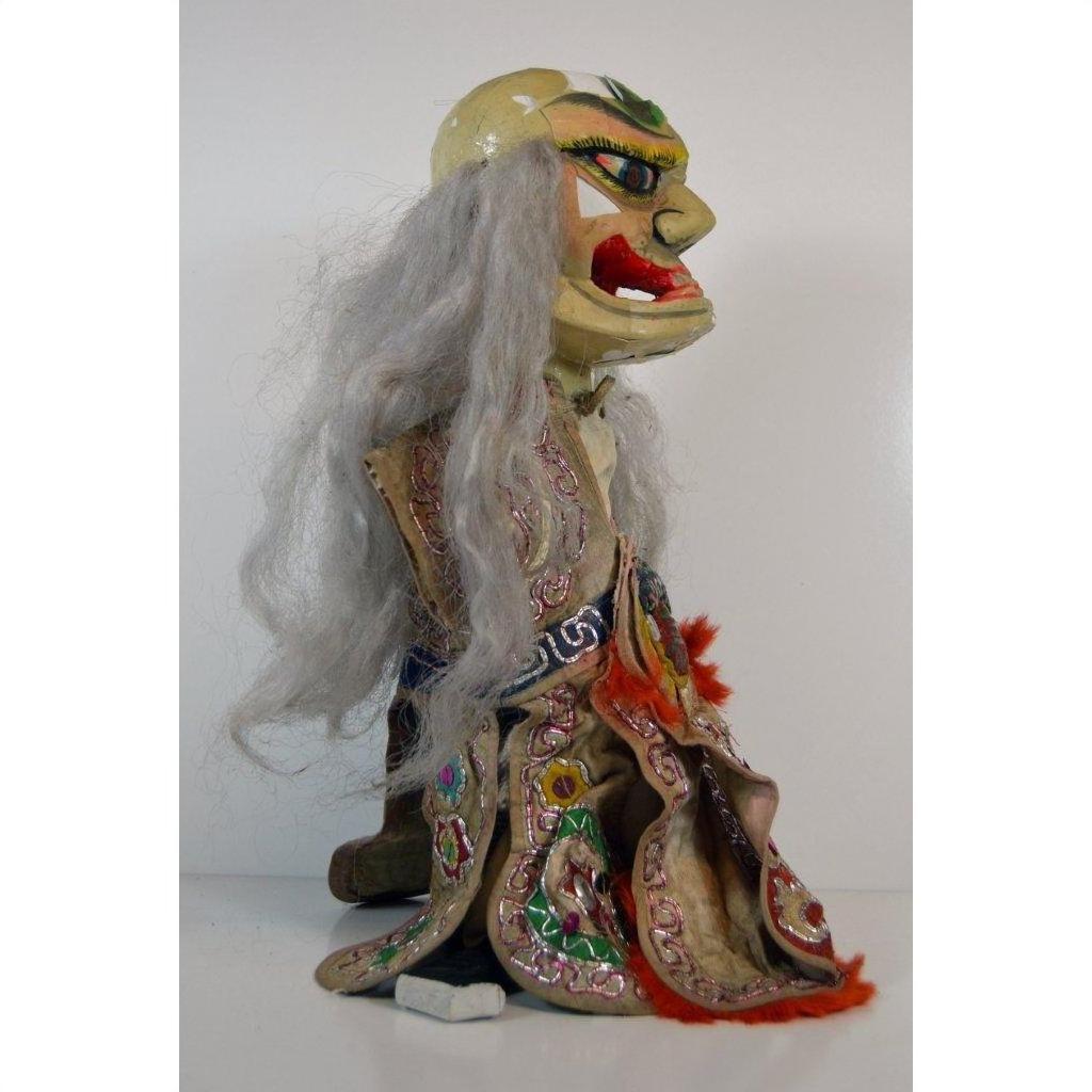 Gray-haired porcelain doll wearing ornate robe, seated against a plain white background.