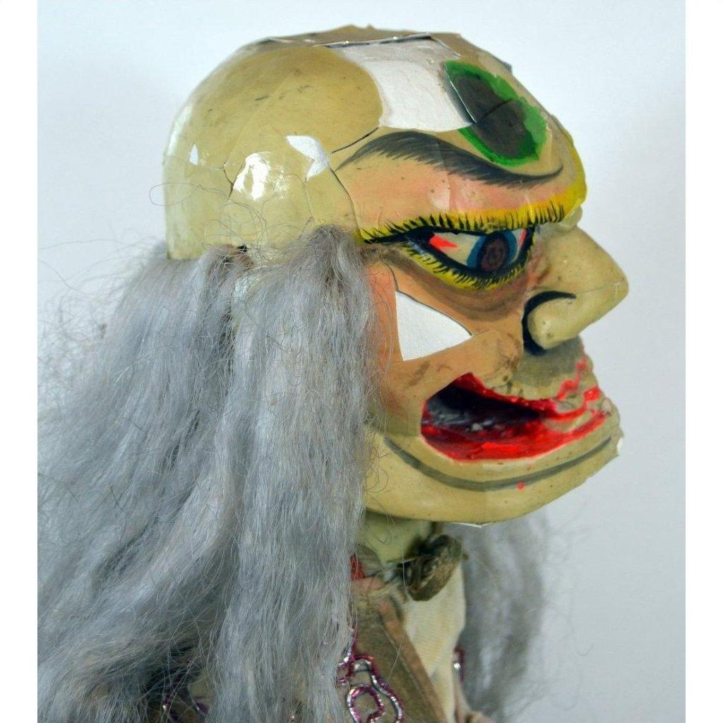 Gray ceramic opera doll with bold makeup and cracked head, side view.