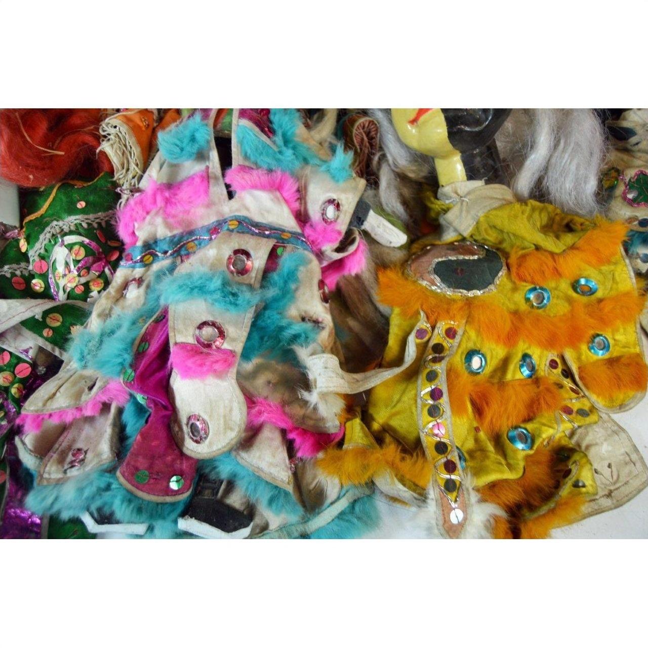Blue, pink, and orange faux fur dolls with sequins and patterned fabric costumes on display indoors.