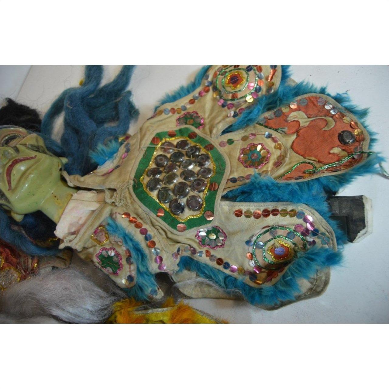 Blue fur-trimmed beaded and sequined doll costume with hand-painted green-face mask, close-up.