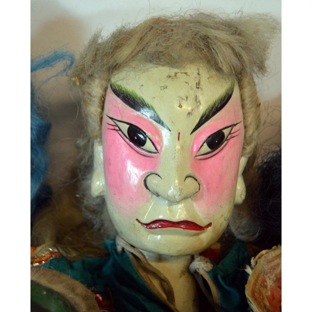 Close-up of a colorful Taiwan Opera Doll, painted face with arched eyebrows and pink cheeks, detailed features visible.