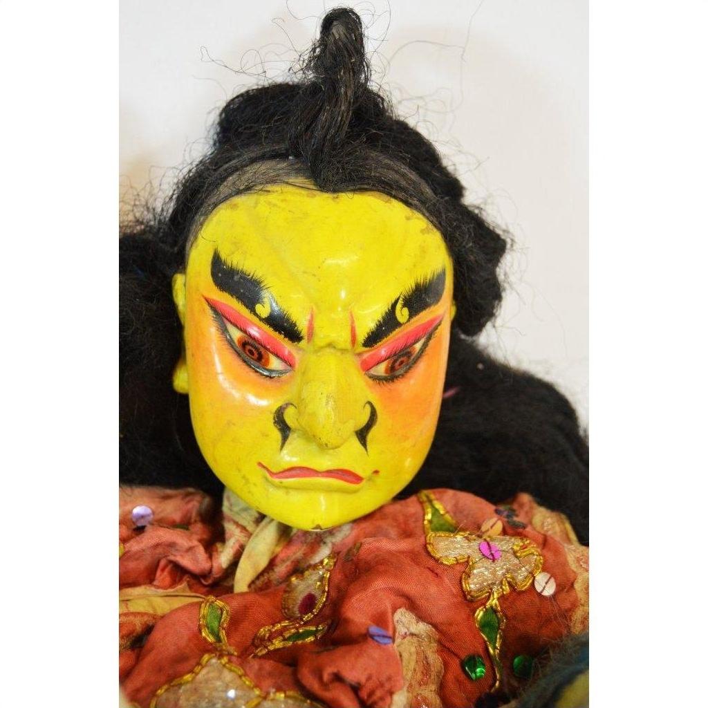 Close-up of Taiwan Opera Dolls with yellow hand-painted faces, black hair, and colorful embroidered clothing.
