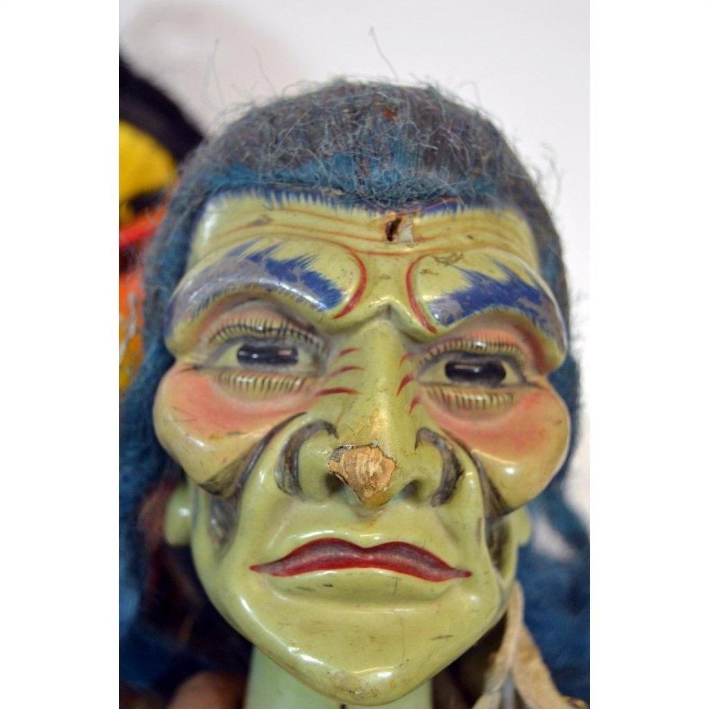 Close-up of a green, wrinkled mask Taiwan Opera Doll with blue hair and red lips, styled with exaggerated features.