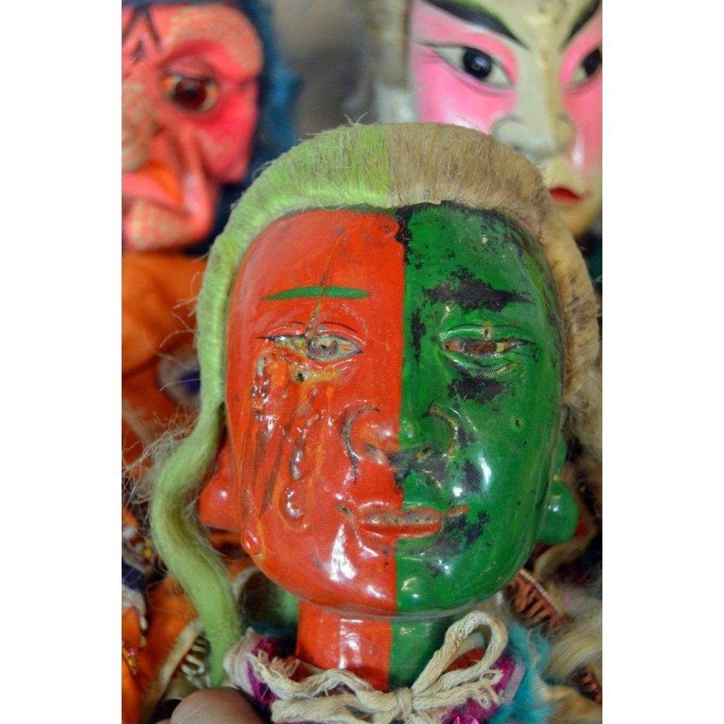 Hand-painted ceramic Taiwan Opera Doll with red and green face, vintage Asian dolls in background on a shelf.
