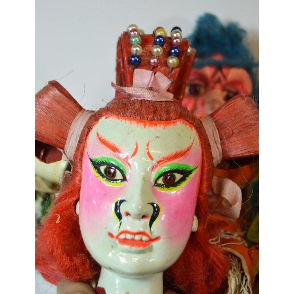 Red and pink Taiwan Opera dolls with hand-painted masks, beaded crowns, and red hair, close-up on a neutral background.