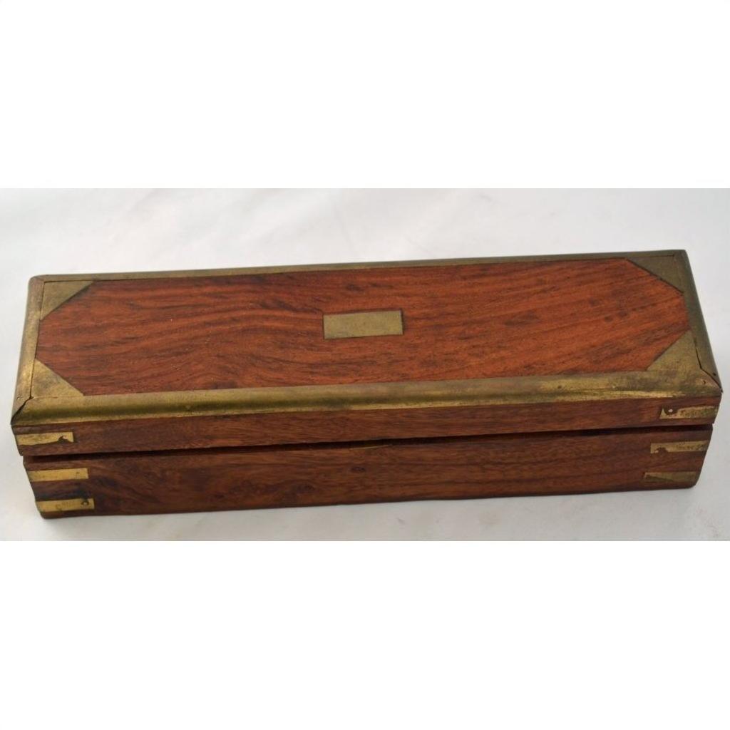 Brown teakwood pencil and jewelry box with brass accents and nameplate, closed, on a light background.