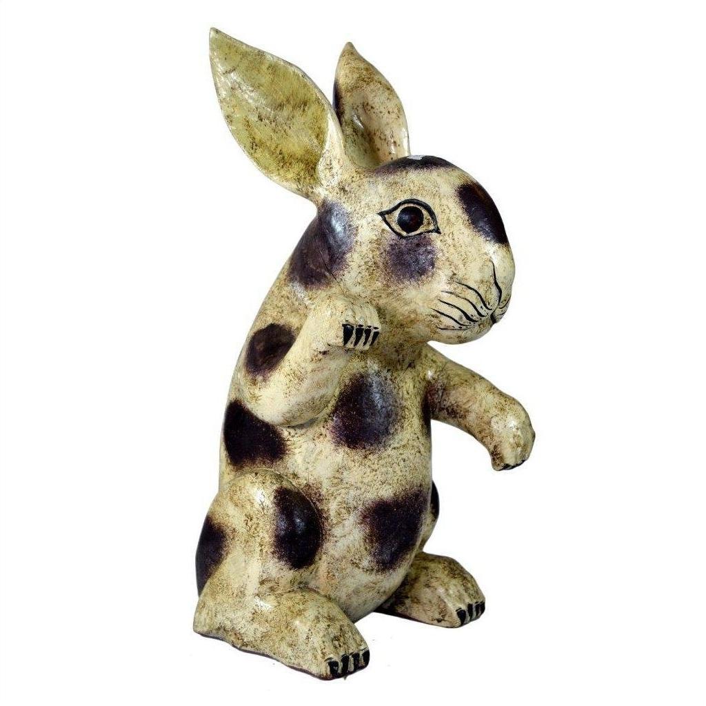 Close-up of a hand-painted ceramic rabbit figurine with upright ears, dark spots, and earthy tones.