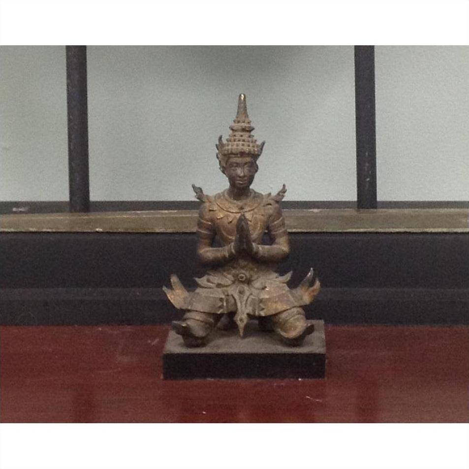 Bronze Thai sculpture of kneeling figure in traditional attire with hands together, close-up view.