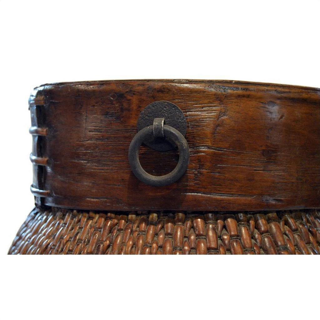 Close-up of brown wood and metal Thai grain basket with rim and metal ring handle, side view.