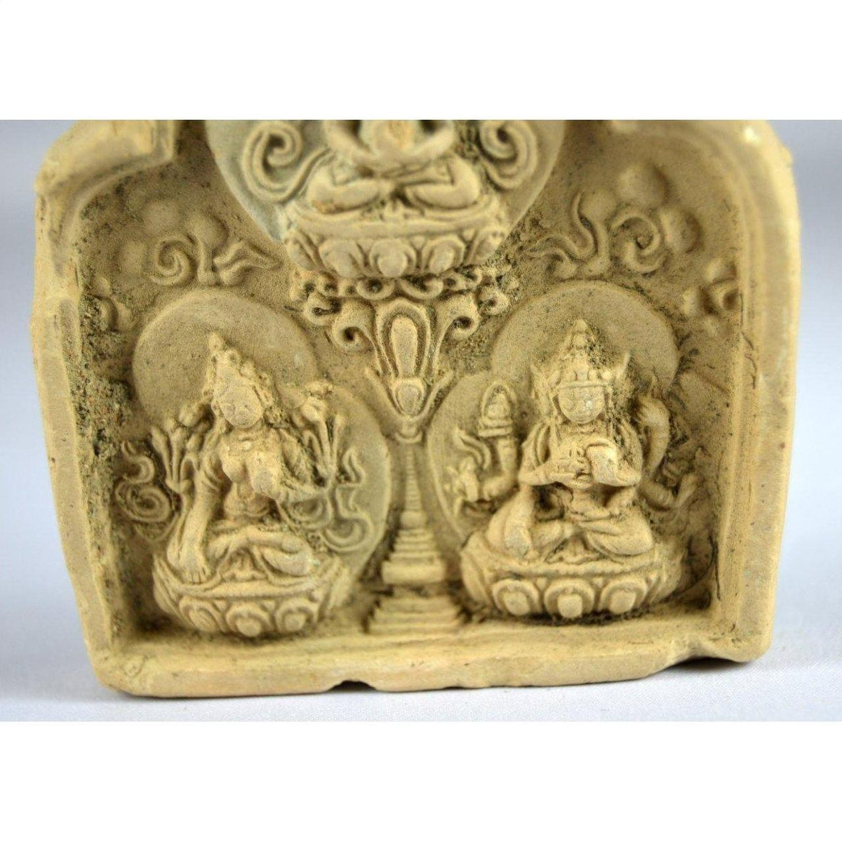 Gray stone carved relief showing two seated deities with ornate patterns, Thai Miniature Terracotta Shrine style, close-up.