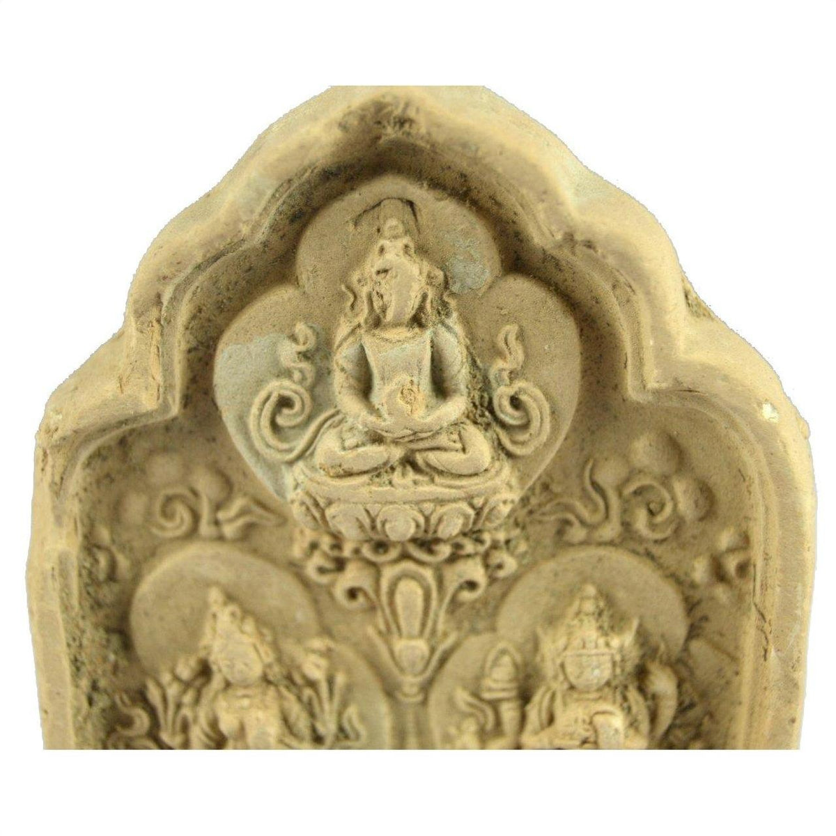 Close-up of an ornate stone terracotta relief featuring a seated figure in meditation, Thai shrine style.