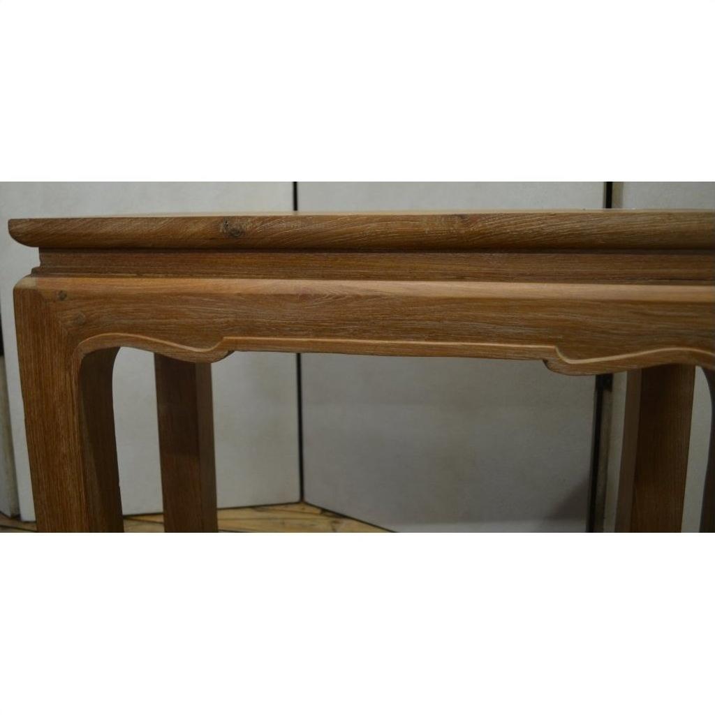 Close-up of brown teak wood table with carved edges and horse hoof feet against a plain background.