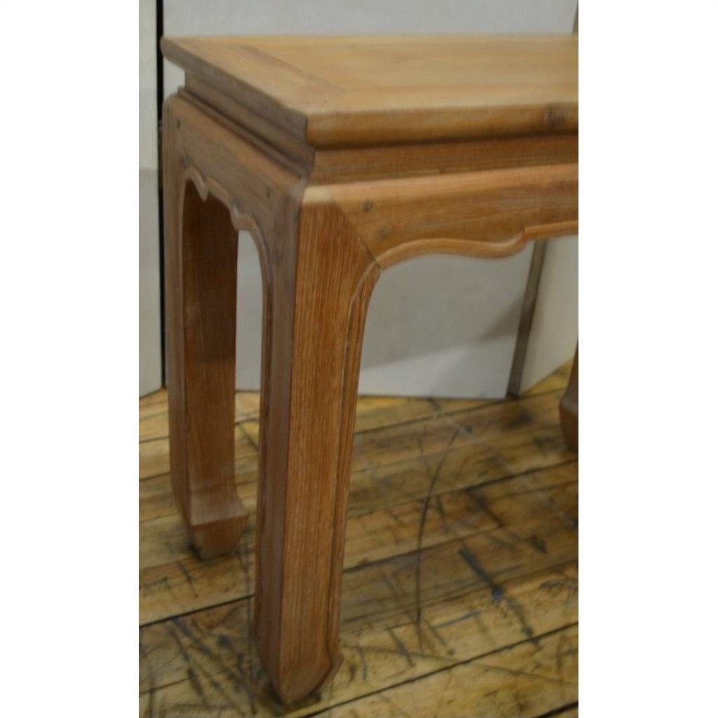 Close-up of brown teak wood Thai table with horse hoof feet on a rustic wooden floor.