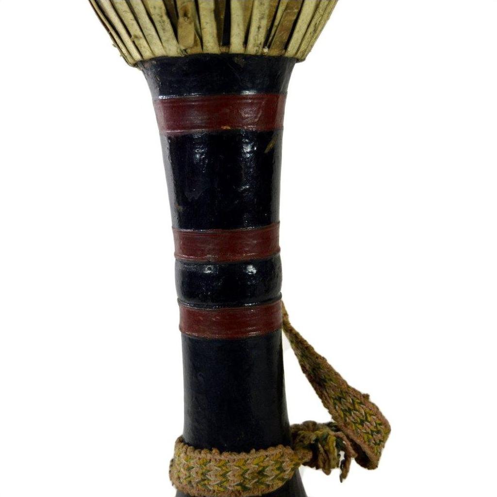 Close-up of black Thai tribal bongo drum with red bands and woven strap in good condition, against white background.