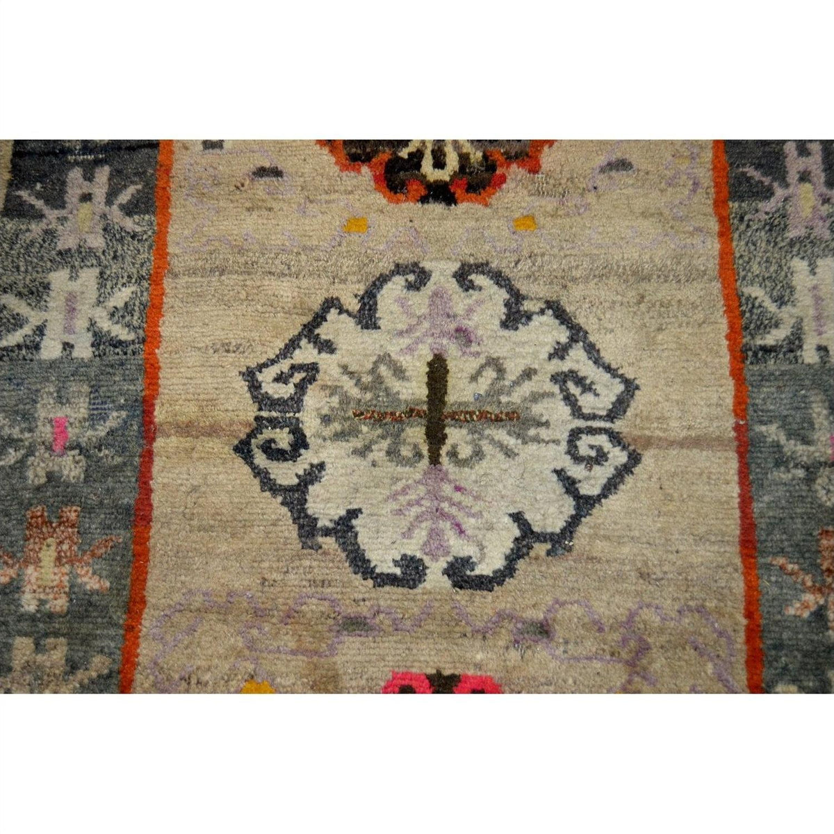 Close-up of a multicolored wool Tibetan praying rug with central floral motif and muted decorative borders, 63" x 36".