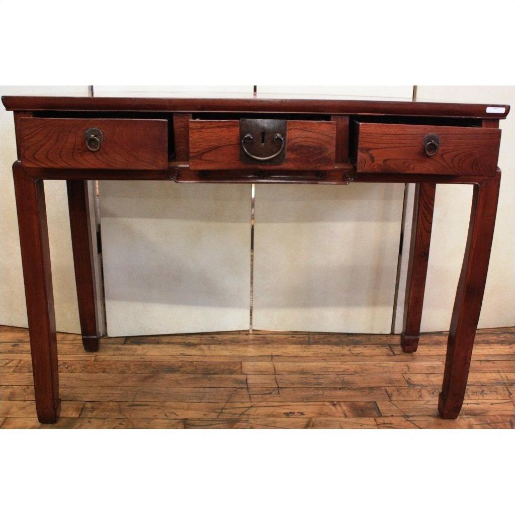 Brown wood triple drawer desk with bronze hardware and horse hoof feet, set on a wooden floor.