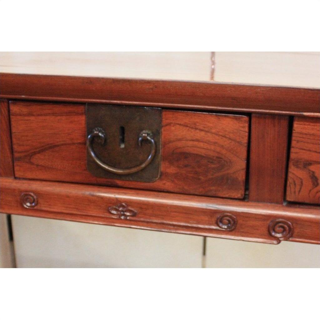 Close-up of antique elmwood desk drawer with metal handle, keyhole, and decorative carvings.