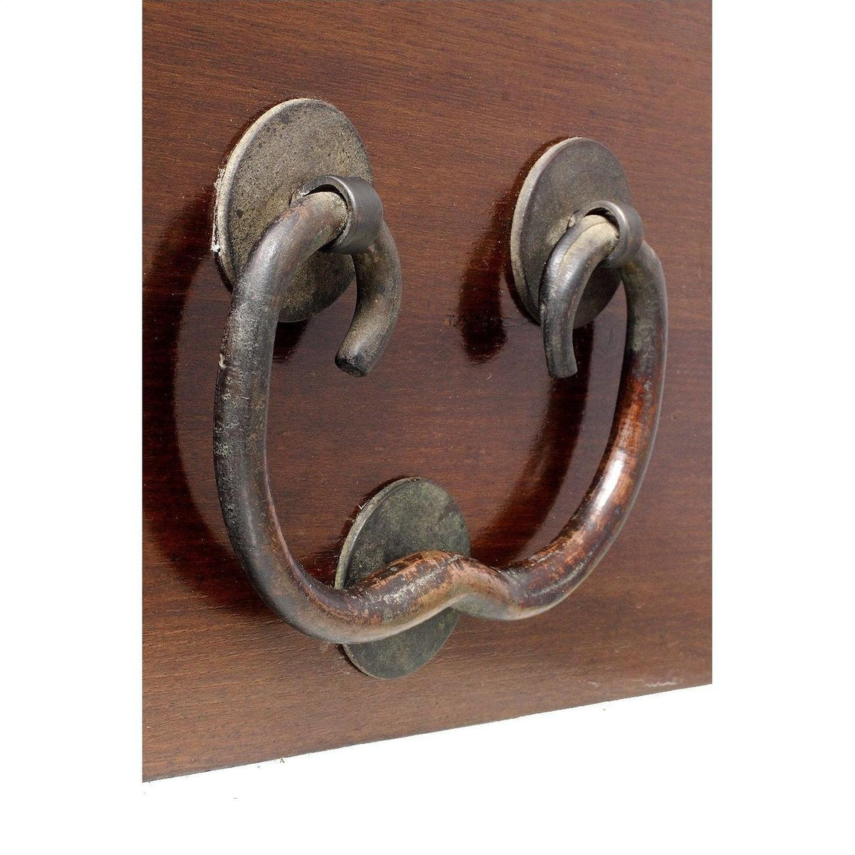 Close-up of a large rustic metal door knocker with a curved handle mounted on natural wood.