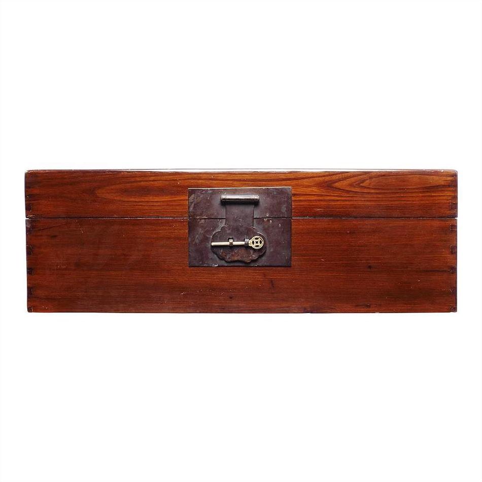 Rectangular natural wood trunk with dark metal lock against a white background.