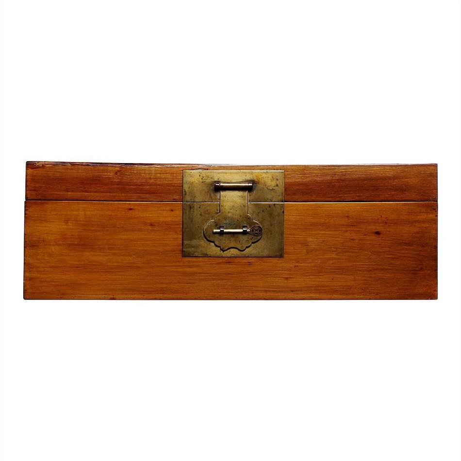 Brown elmwood trunk with brass hardware and large brass front latch, close-up view.