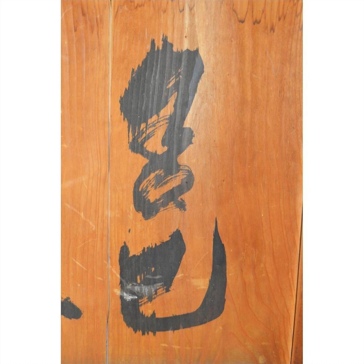 Light brown wooden Chinese divider with vertical planks, hand-painted black calligraphy, antique finish.