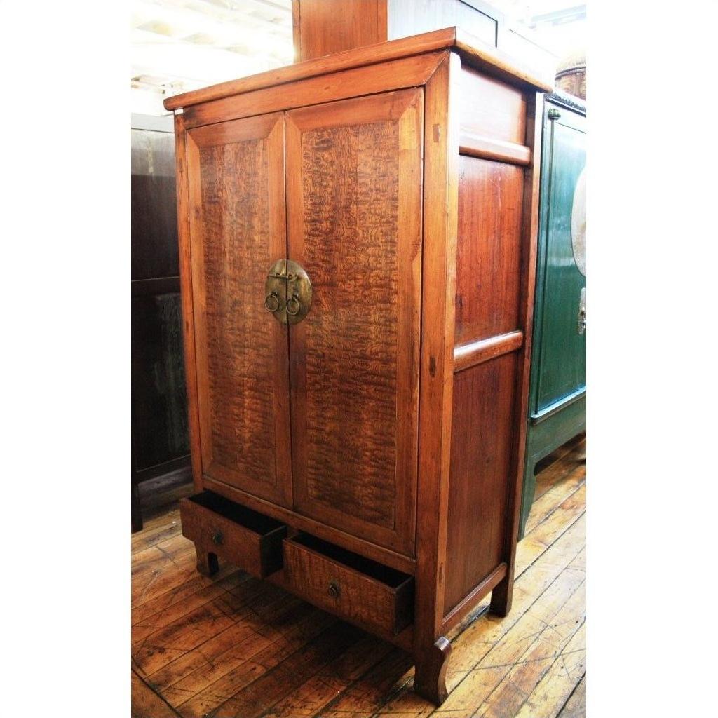 Brown burl wood cabinet with two doors and two open drawers on a wooden floor.
