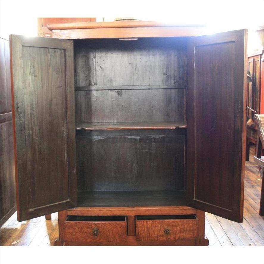 Brown burl wood cabinet with two doors, shelves, and bottom drawers on a wooden floor.