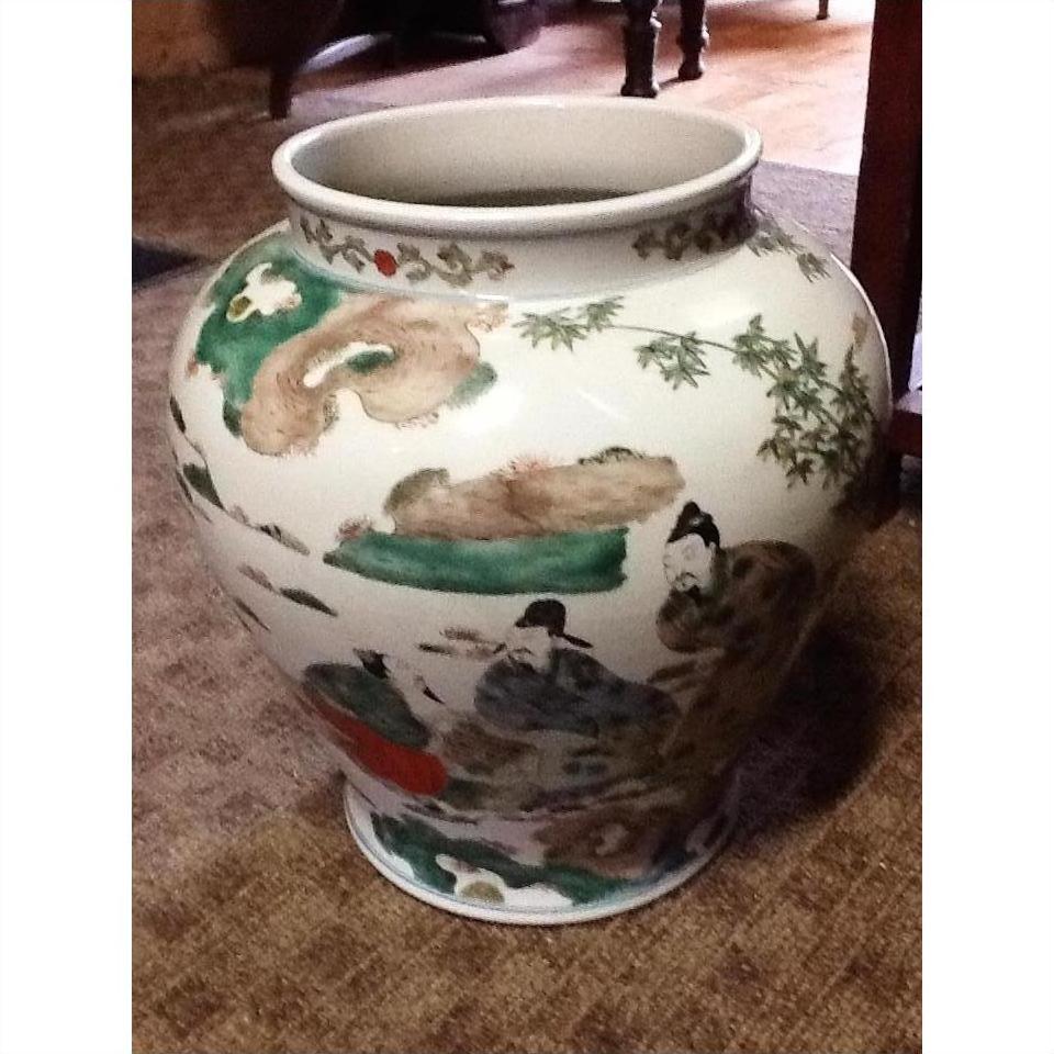 Multicolored painted ceramic urn with Asian figures and nature motifs, displayed on a carpet.