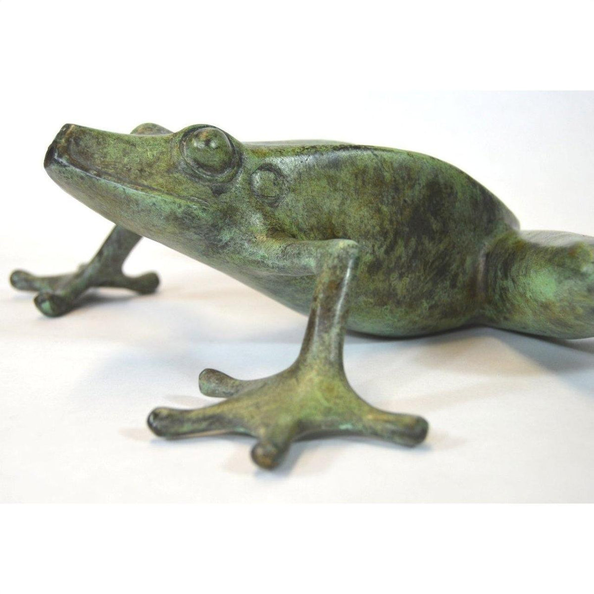 Verde gris bronze pond frog sculpture with outstretched leg on white background, close-up view.