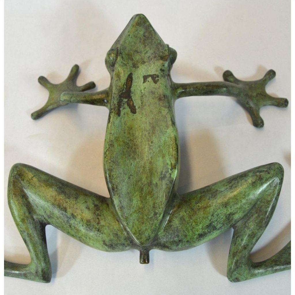 Verde gris bronze frog figurine outstretched on a light background.